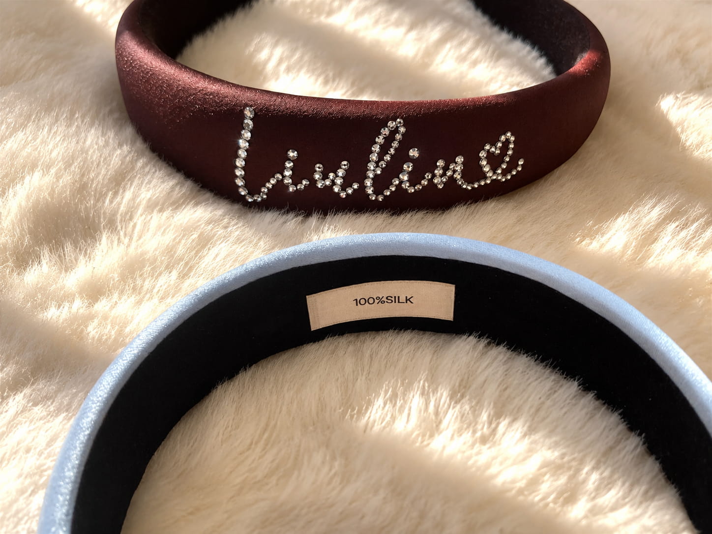 Inner view of personalized silk padded headband showing 100% silk label on a soft plush background.