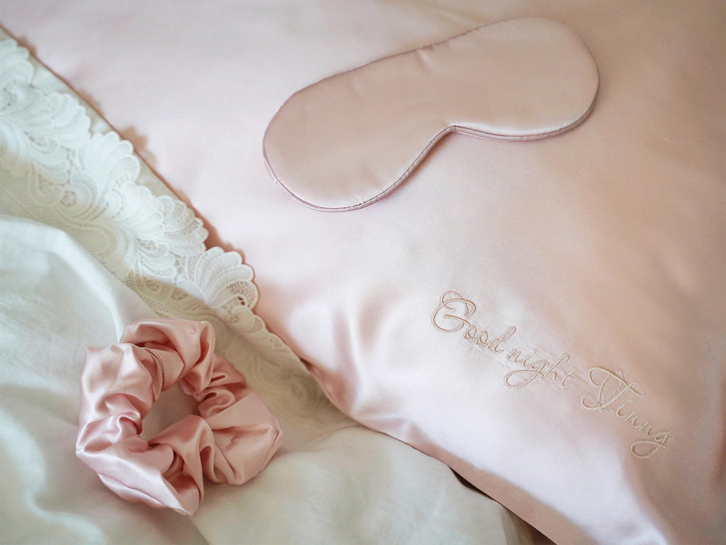 Personalized silk pillowcase on bed with matching silk sleep mask and scrunchie
