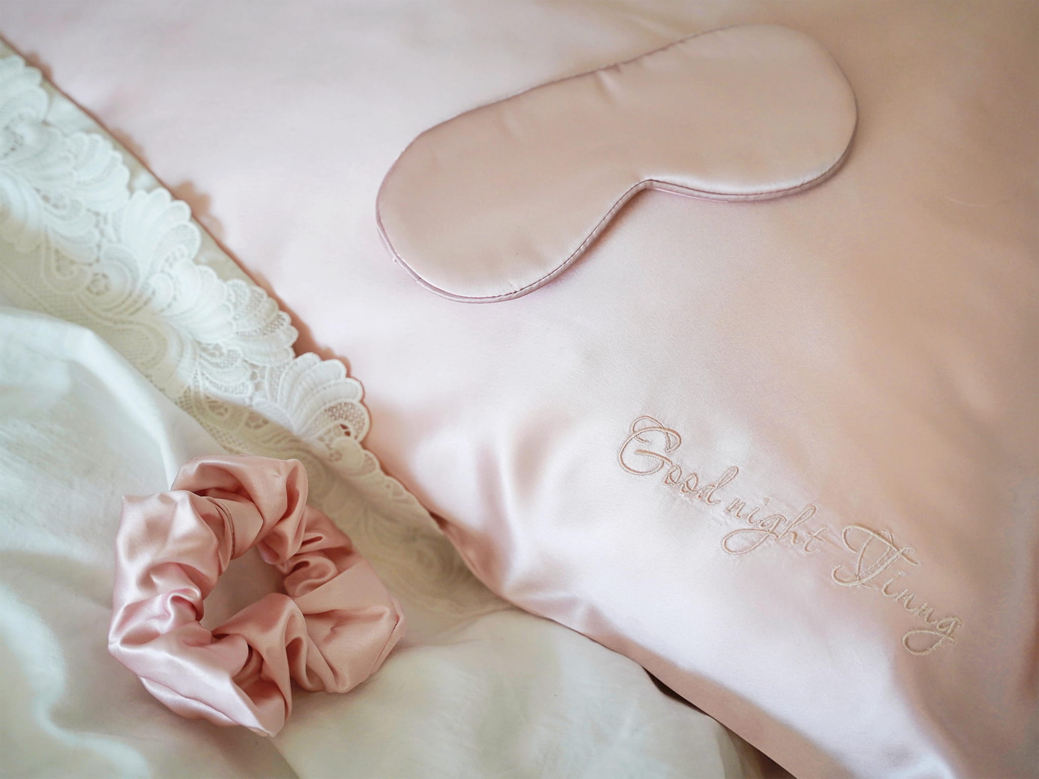 Personalized silk pillowcase on bed with matching silk sleep mask and scrunchie