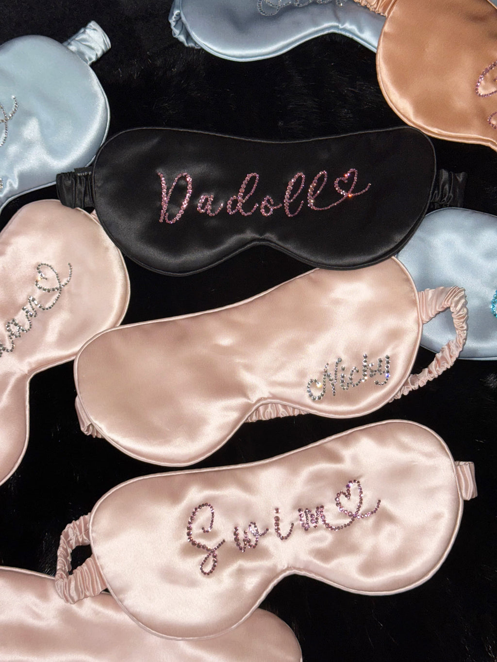 Personalized 22 momme silk sleep masks with custom rhinestone names in pink, black, and blue.