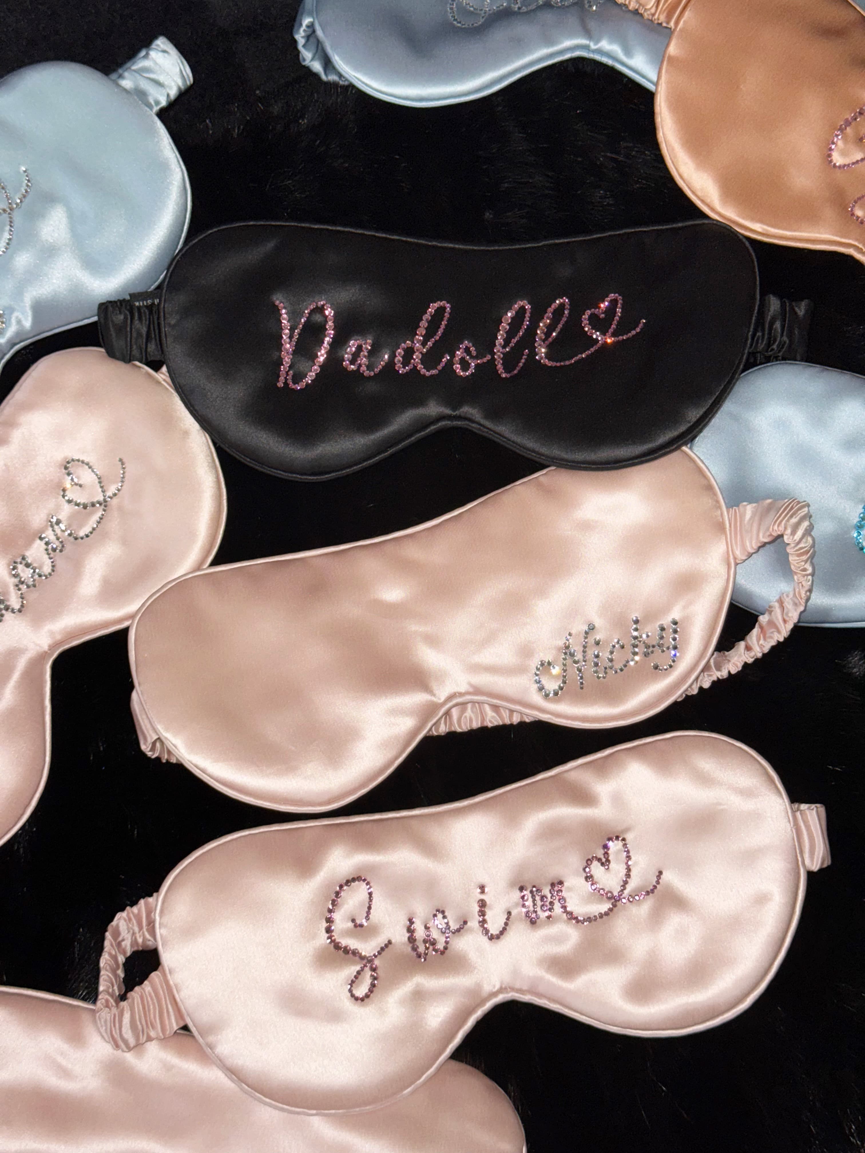 Personalized 22 momme silk sleep masks with custom rhinestone names in pink, black, and blue.