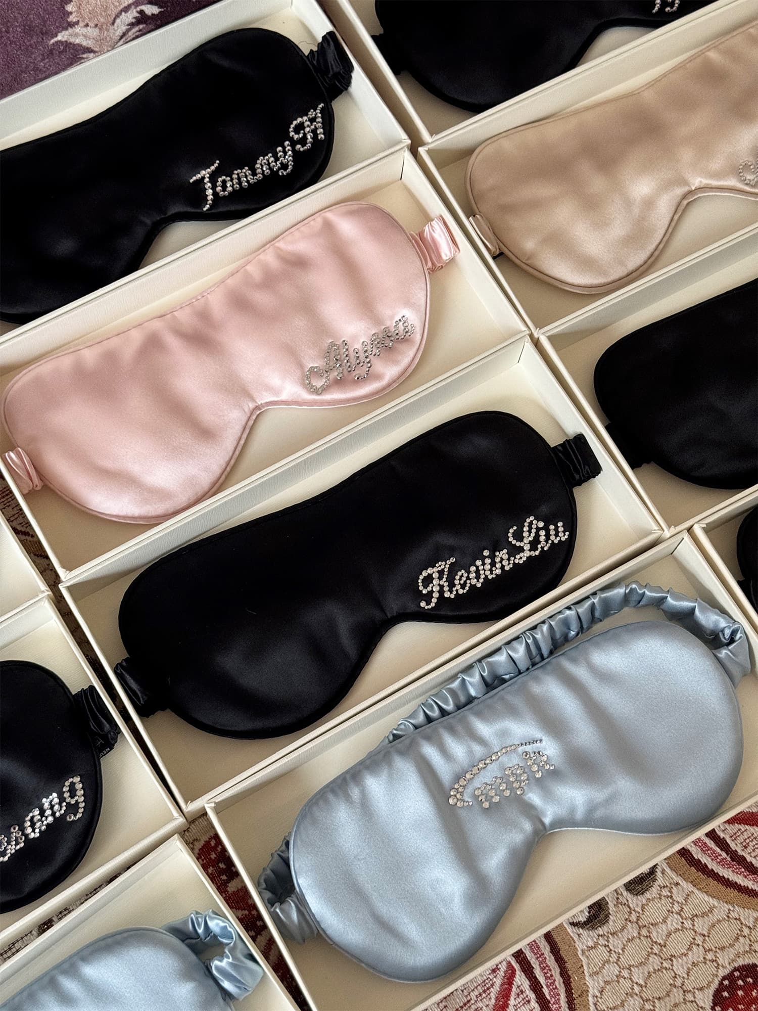 Personalized 22 momme silk sleep masks with rhinestone names displayed in luxury gift boxes.