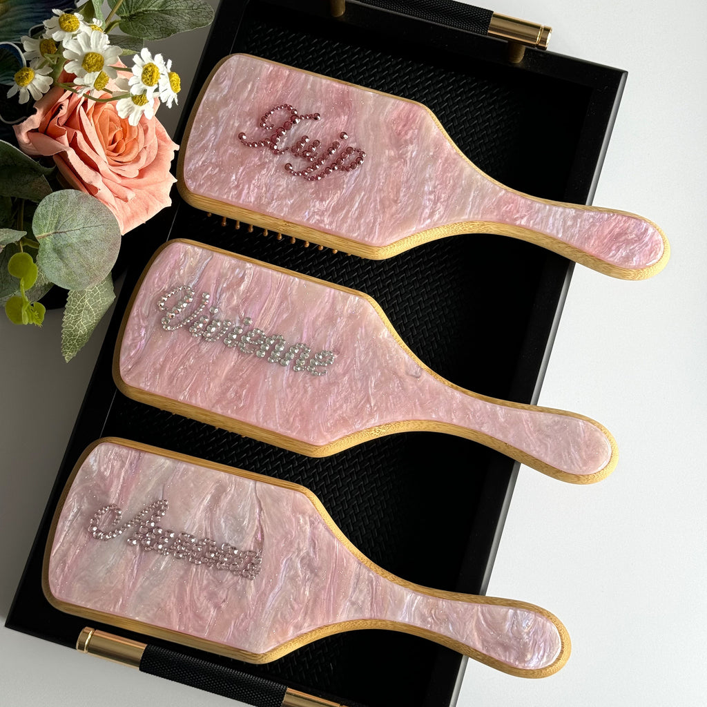Trio of pink marble paddle brushes with personalized names in dark pink and brilliant silver rhinestones.