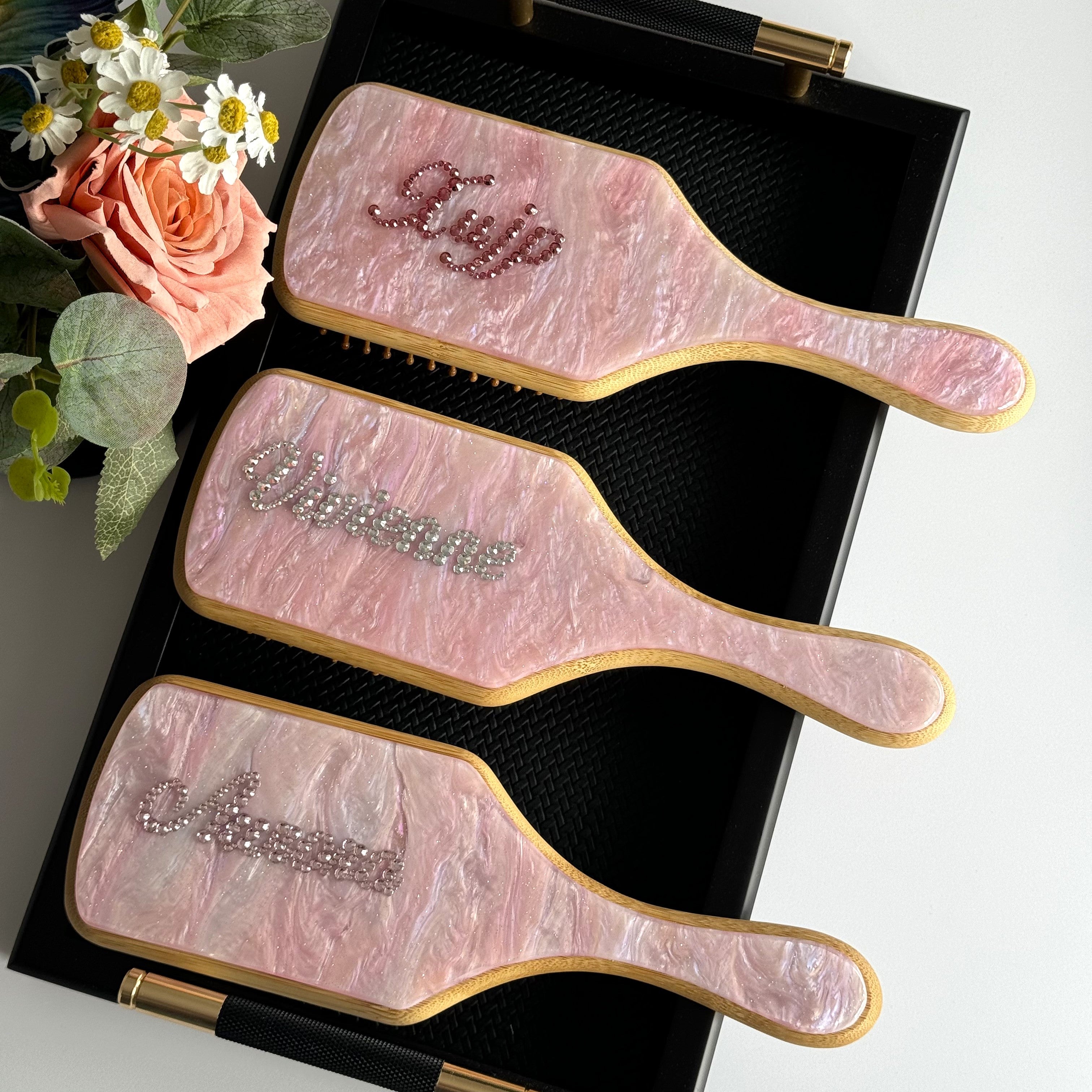 Trio of pink marble paddle brushes with personalized names in dark pink and brilliant silver rhinestones.