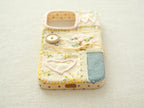 Bottom view of the "Floral Heart" patchwork case with a charging port cutout and yellow hand-stitched border.