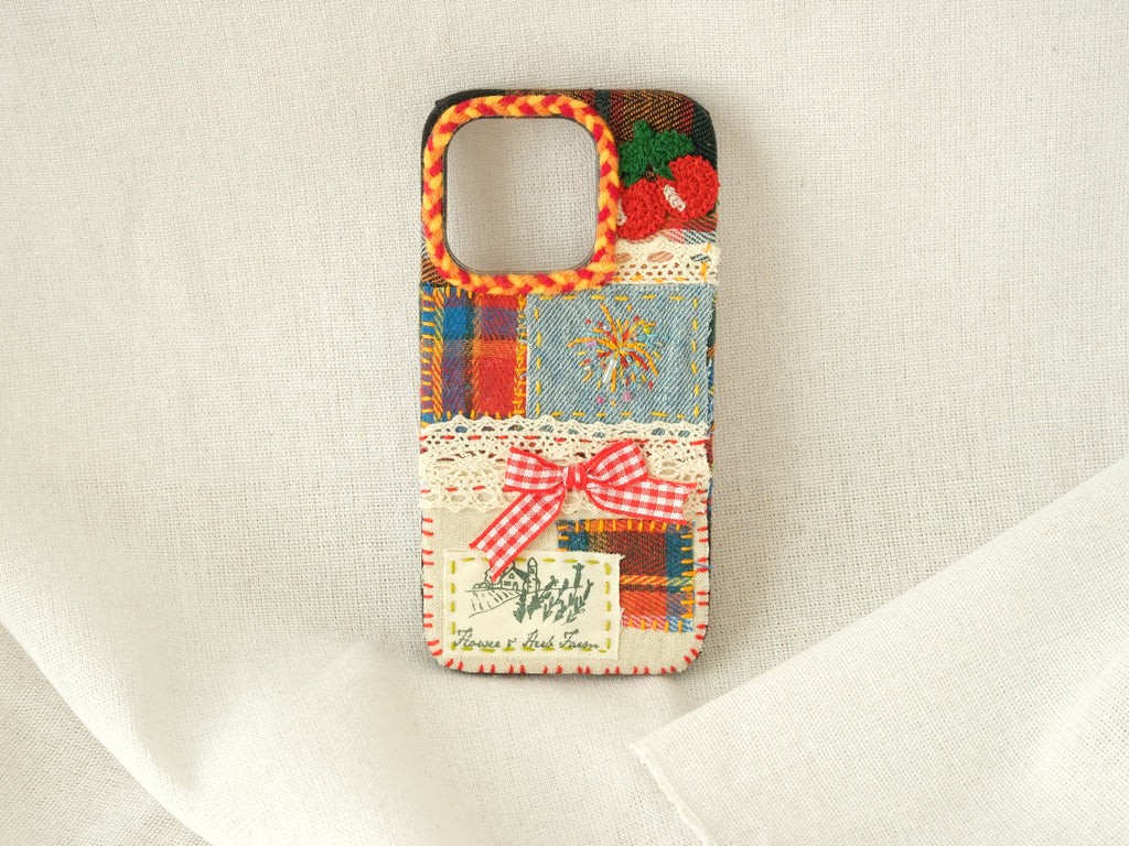 Handmade patchwork phone case with 3D embroidered cherries, fireworks patterns, and a red gingham bow.