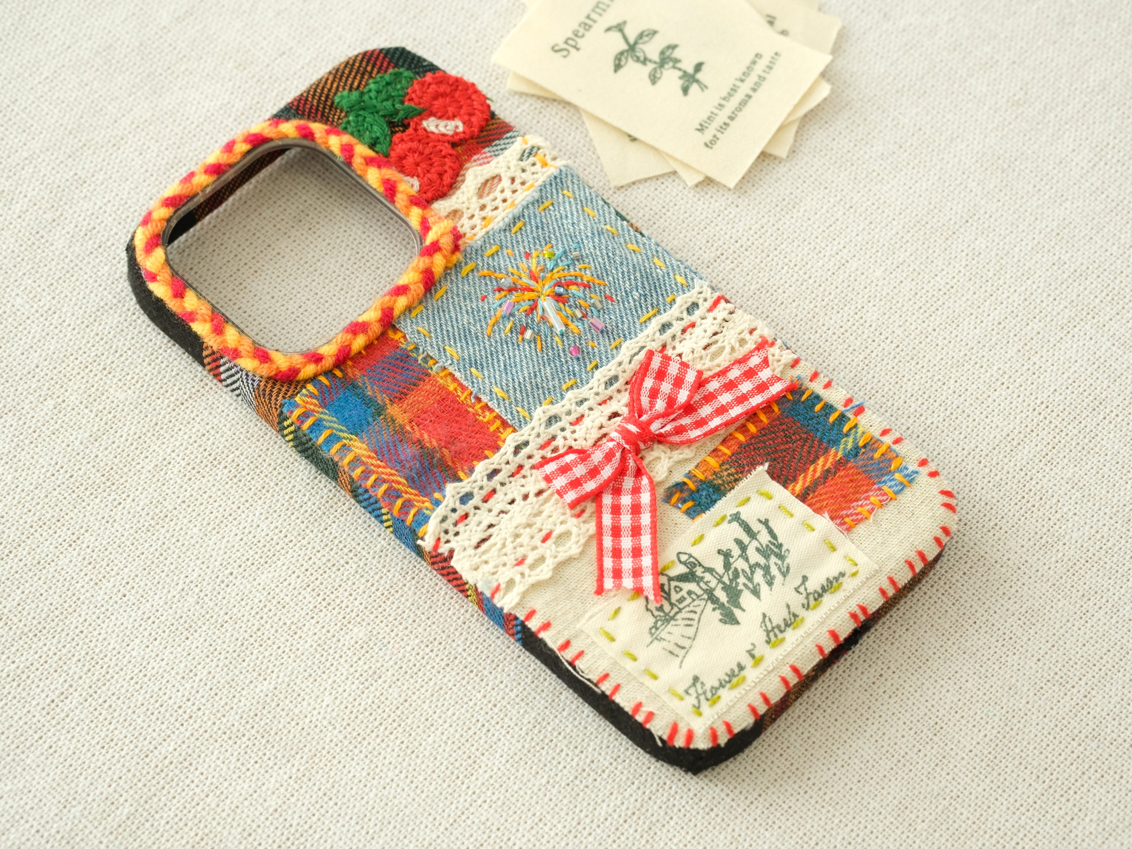 Side view of the patchwork case featuring 3D cherries, a red bow, and a hand-braided camera border.