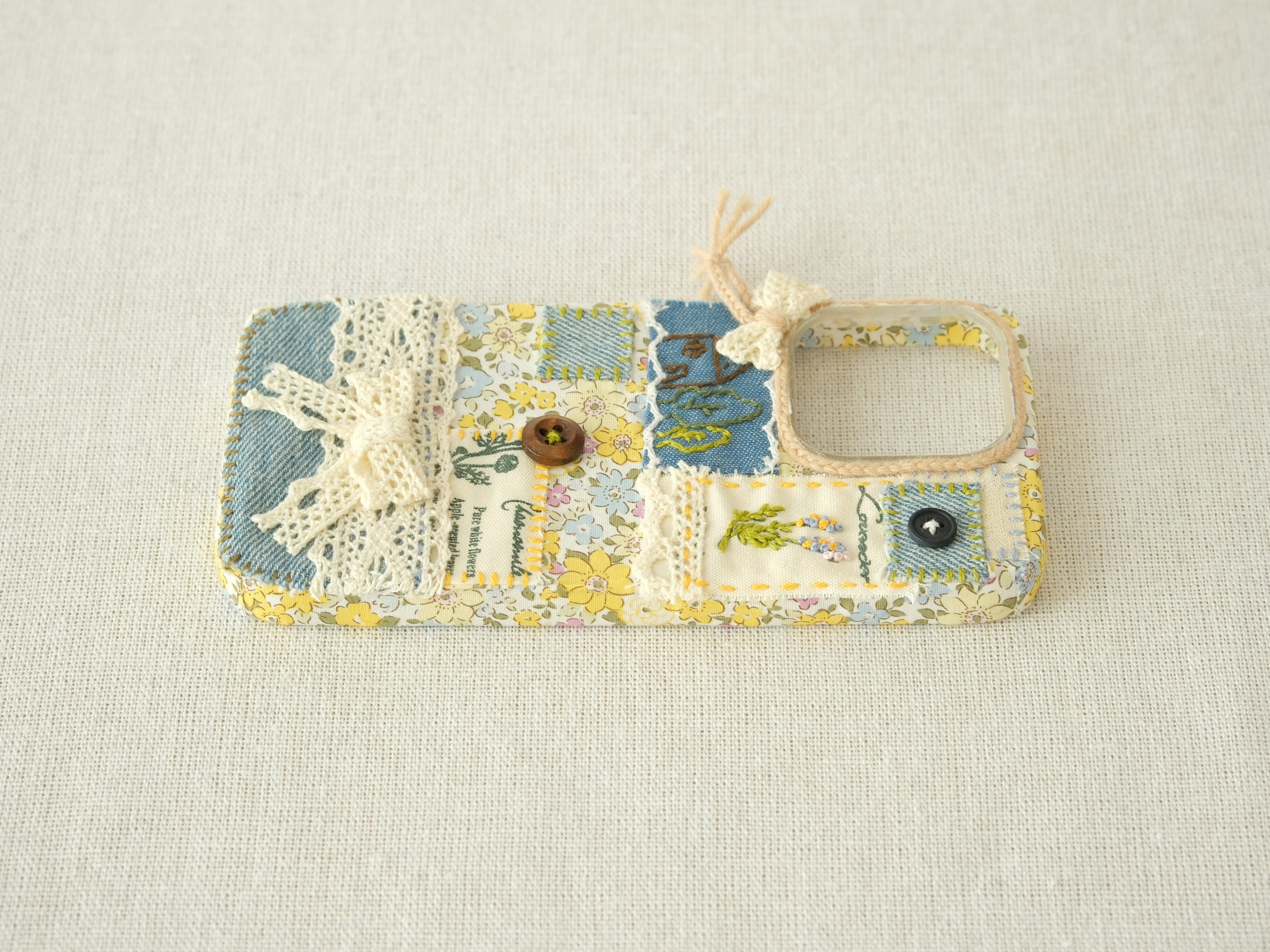 Side view of the patchwork case showing volume button access and artisanal stitching details.