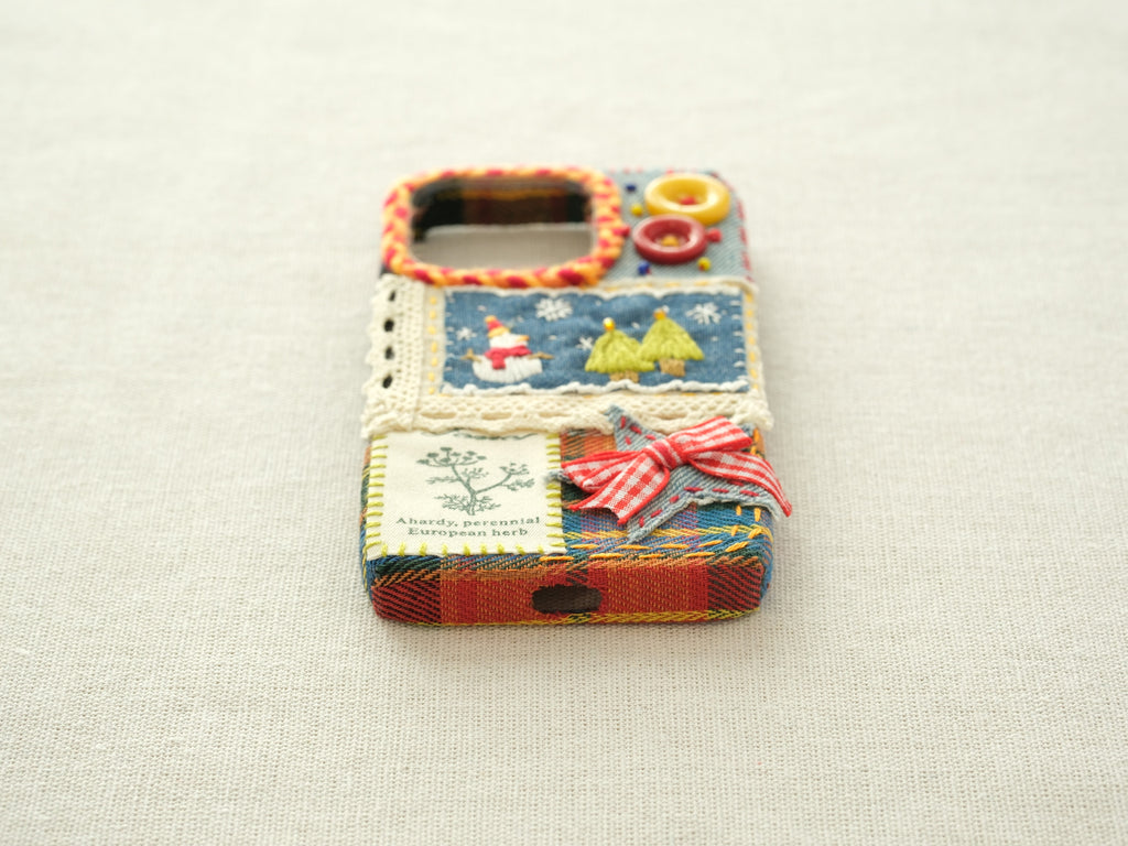 Bottom view of the snowman patchwork case with a charging port cutout and a yellow hand-stitched blanket stitch border.