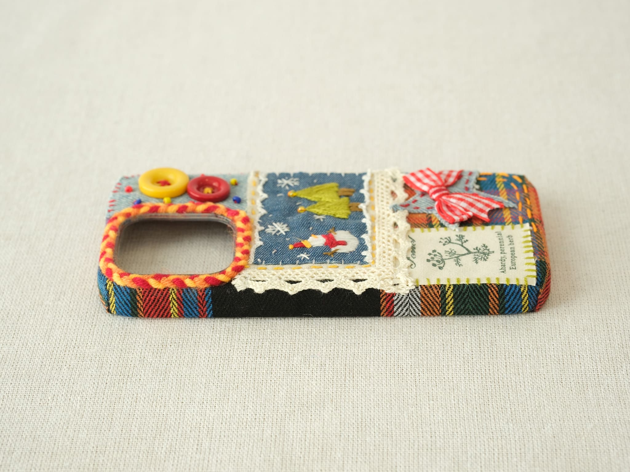 Side view of the snowman patchwork case with a dark plaid fabric texture and button protection.