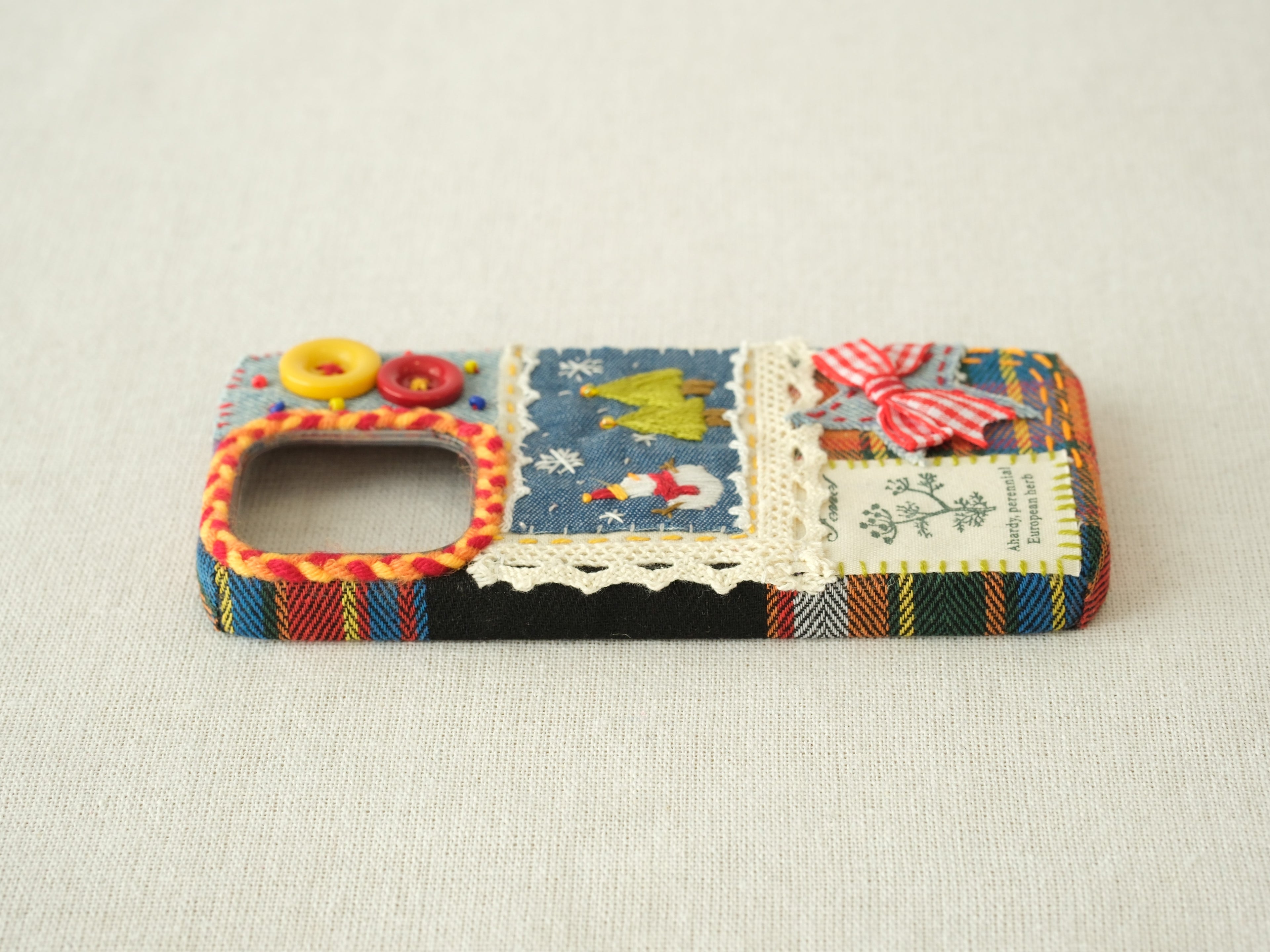 Side view of the snowman patchwork case with a dark plaid fabric texture and button protection.