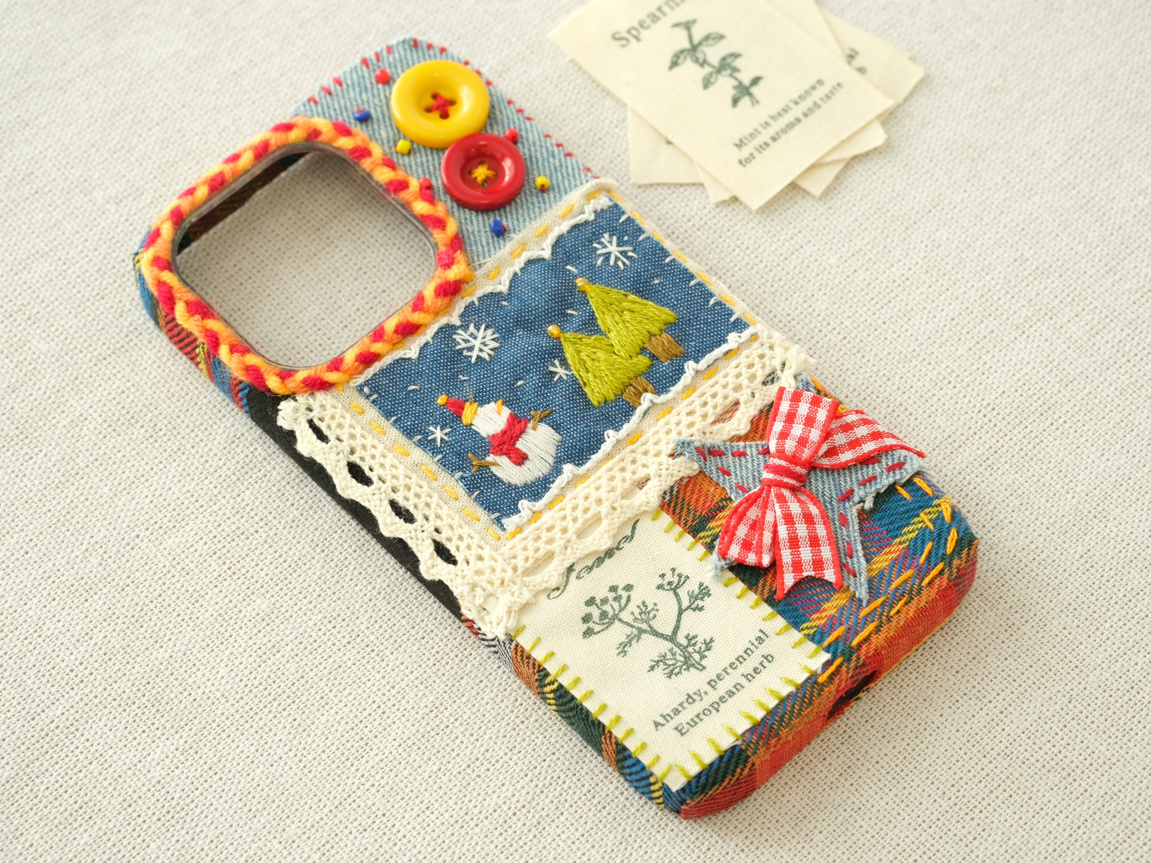 Side view of the patchwork case with a snowman, embroidered trees, and a hand-braided camera border.