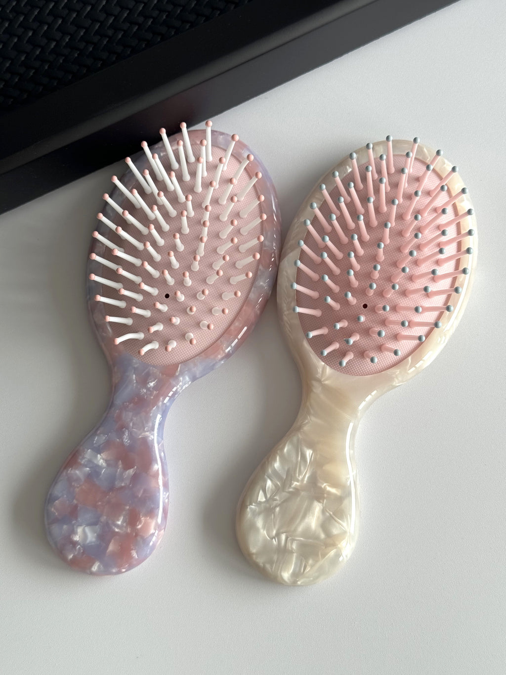 Detail of the mini hair brush featuring round-tip bristles and a cushioned base for a gentle scalp massage.