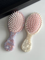 Detail of the mini hair brush featuring round-tip bristles and a cushioned base for a gentle scalp massage.