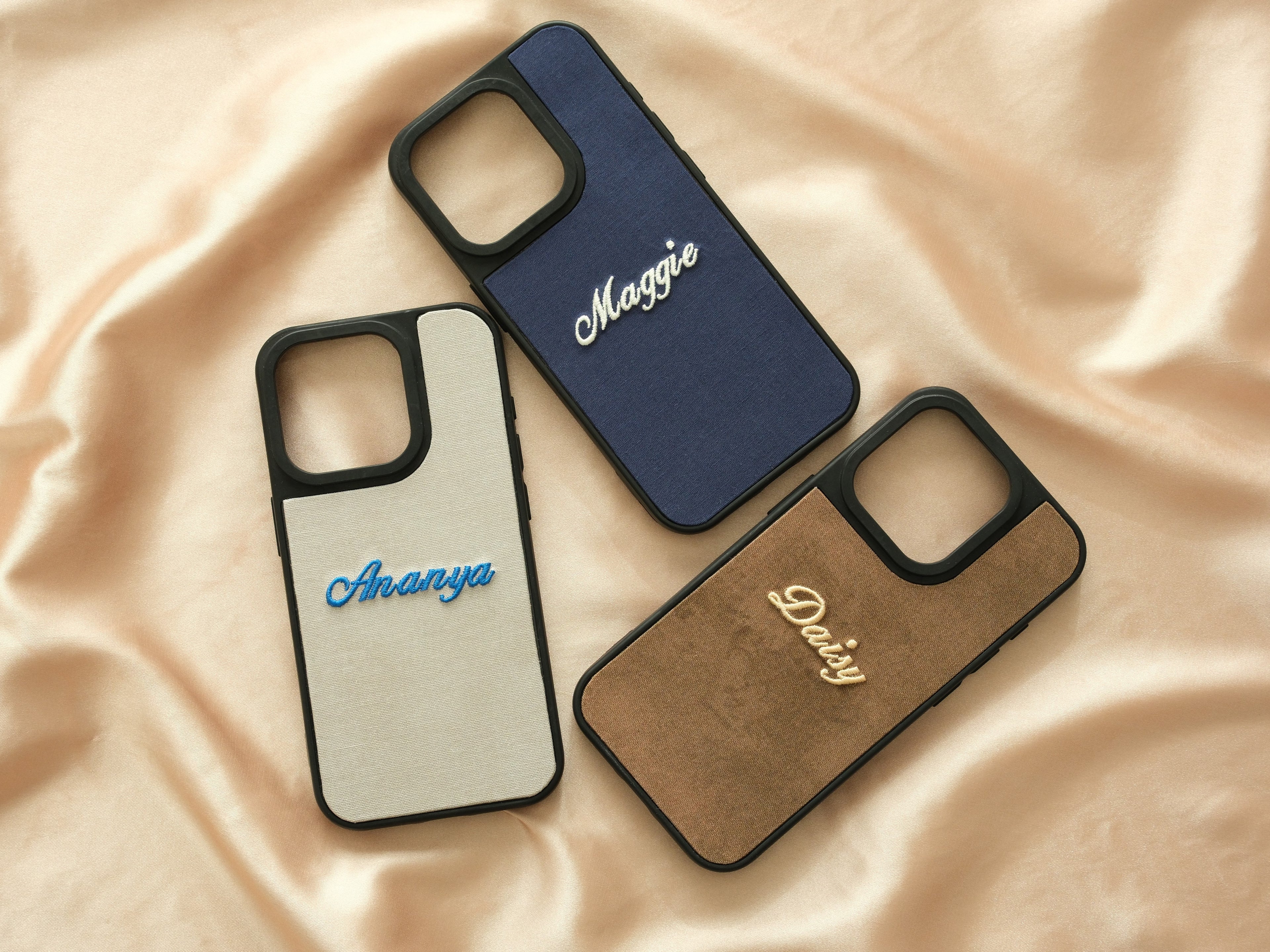 Collection of personalized embroidered cases in blue, cream, and brown—an elegant accessory for smartphones.