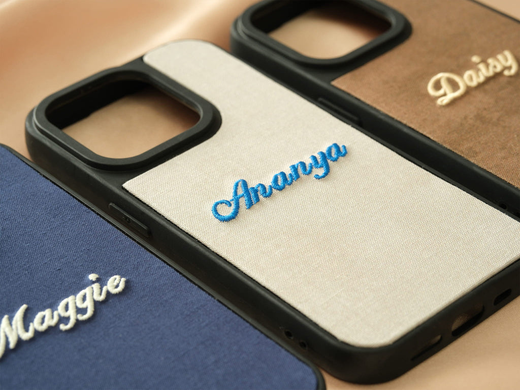 Detail of blue embroidery on a cream fabric case, showing high-quality texture and handcrafted finish.
