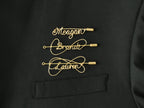 Custom name brooch in gold-plated copper wire on a black jacket, handcrafted jewelry.