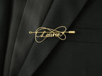 Custom name brooch with elegant double-line intertwined design, in gold-plated copper on a black jacket.