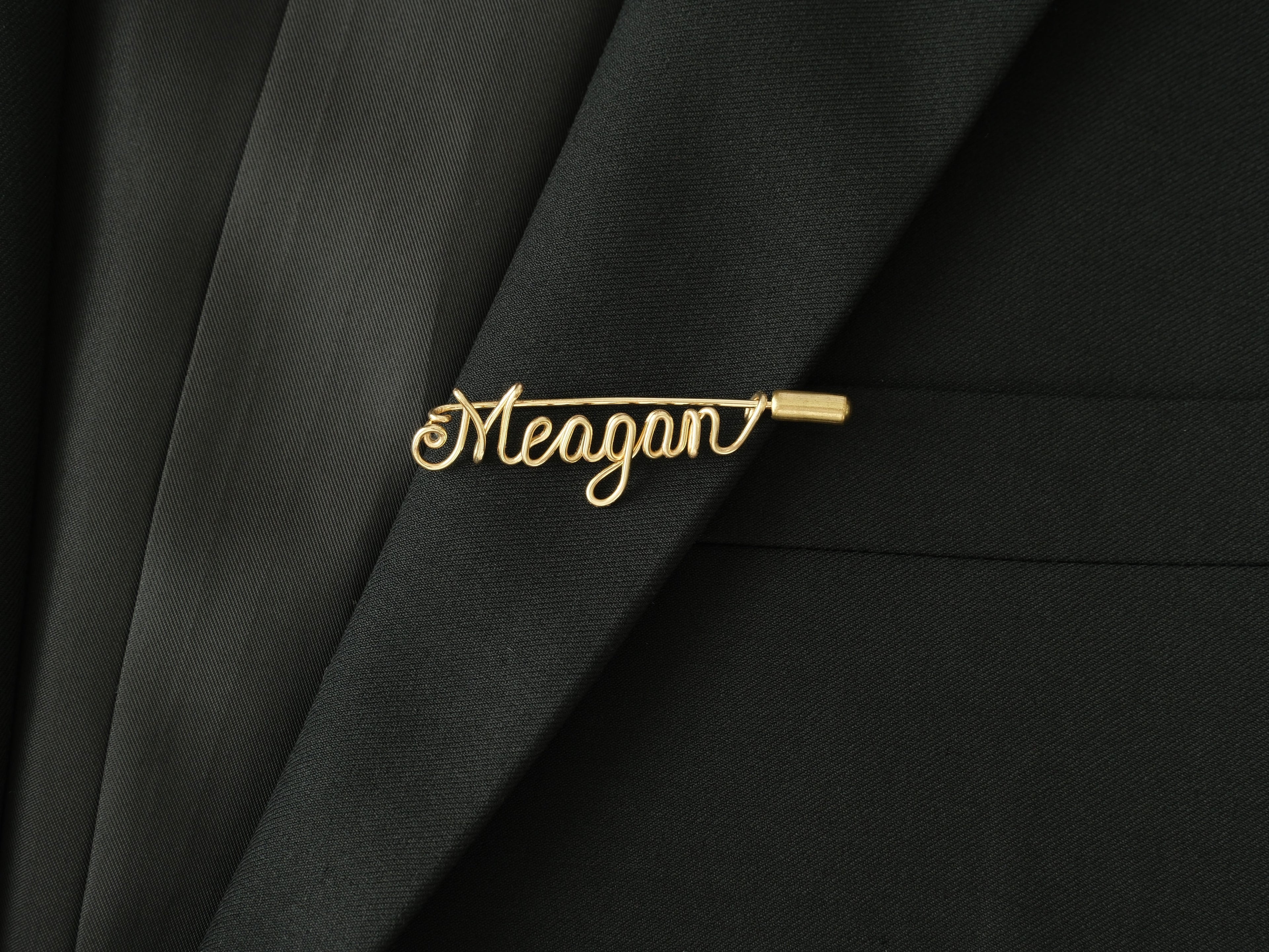 Custom name brooch in minimalist style, handmade in gold-plated copper wire on a jacket lapel.