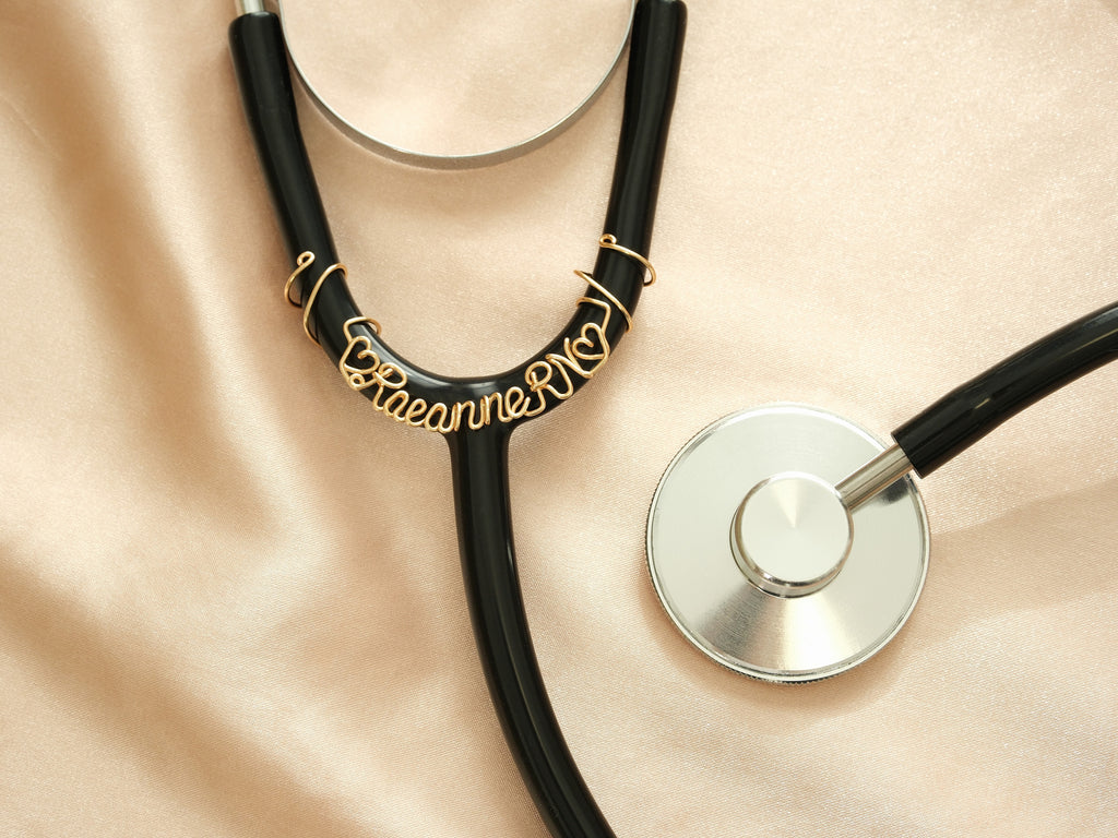 Close-up of a personalized gold stethoscope tag with name and heart symbols, a special gift for Registered Nurses (RN).