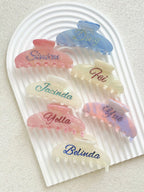 Personalized hair claw clips in pastel and marble colors with colorful rhinestone names, romantic style.