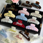 Collection of personalized hair claw clips with rhinestone names in various trendy colors and styles.