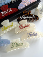 Detail of personalized tortoise shell and pearl white hair clips with glittering rhinestone names.