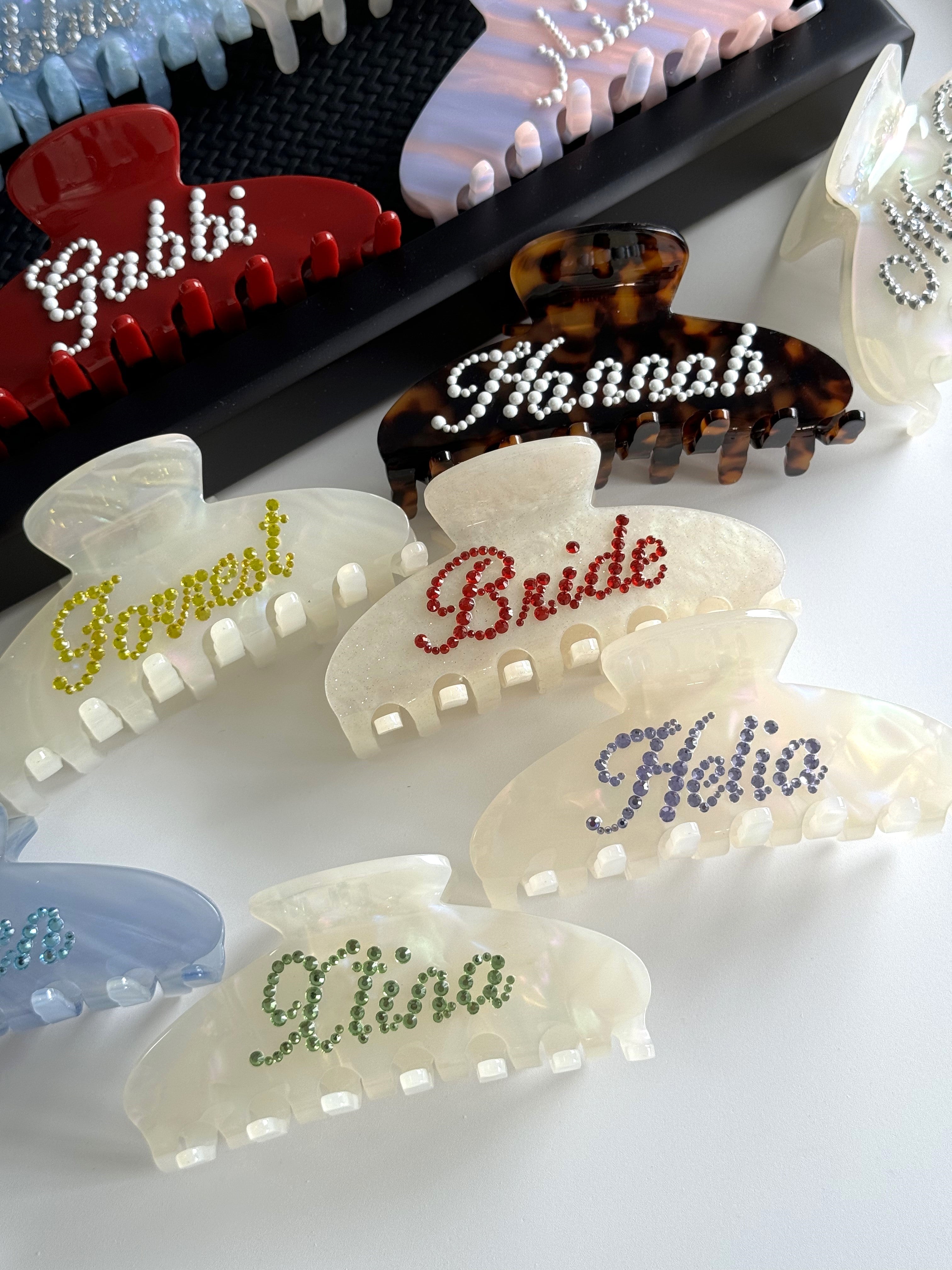 Detail of personalized tortoise shell and pearl white hair clips with glittering rhinestone names.
