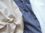 Close-up detail of the natural linen texture in beige and slate blue, showing a breathable and soft fabric.