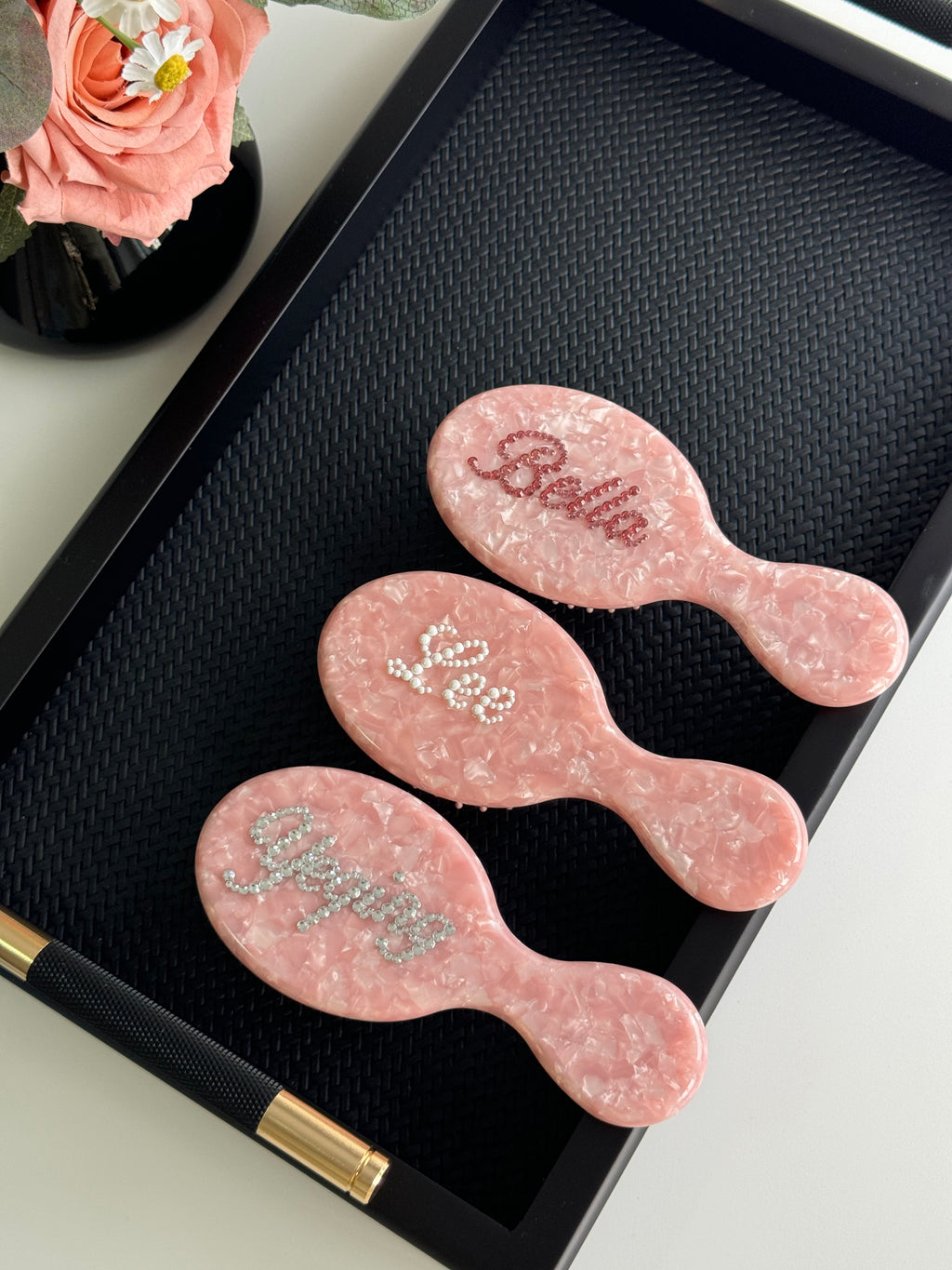 Trio of pink marble mini brushes with personalized names in dark pink, pearl, and silver rhinestones.