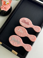 Trio of pink marble mini brushes with personalized names in dark pink, pearl, and silver rhinestones.
