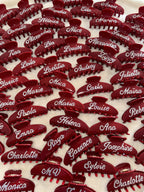 Multiple personalized red hair clips with white rhinestone names, ideal for group gifts.