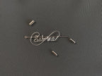 Detailed view of the protective cap closure on a silver-plated name pin over a dark green jacket.