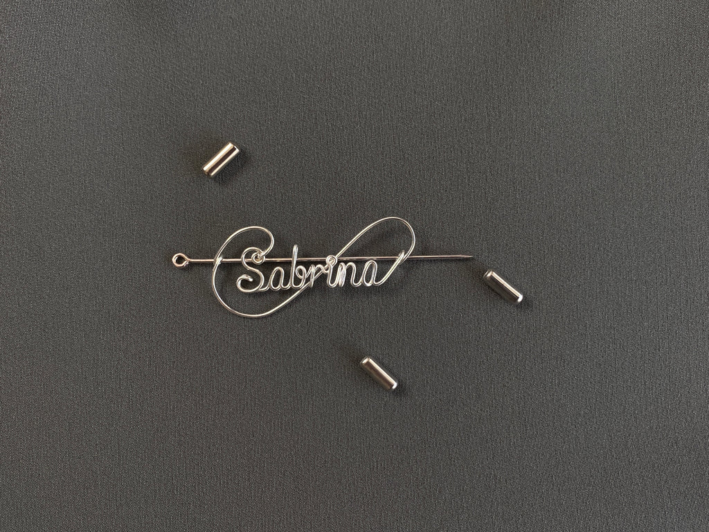 Detailed view of the protective cap closure on a silver-plated name pin over a dark green jacket.