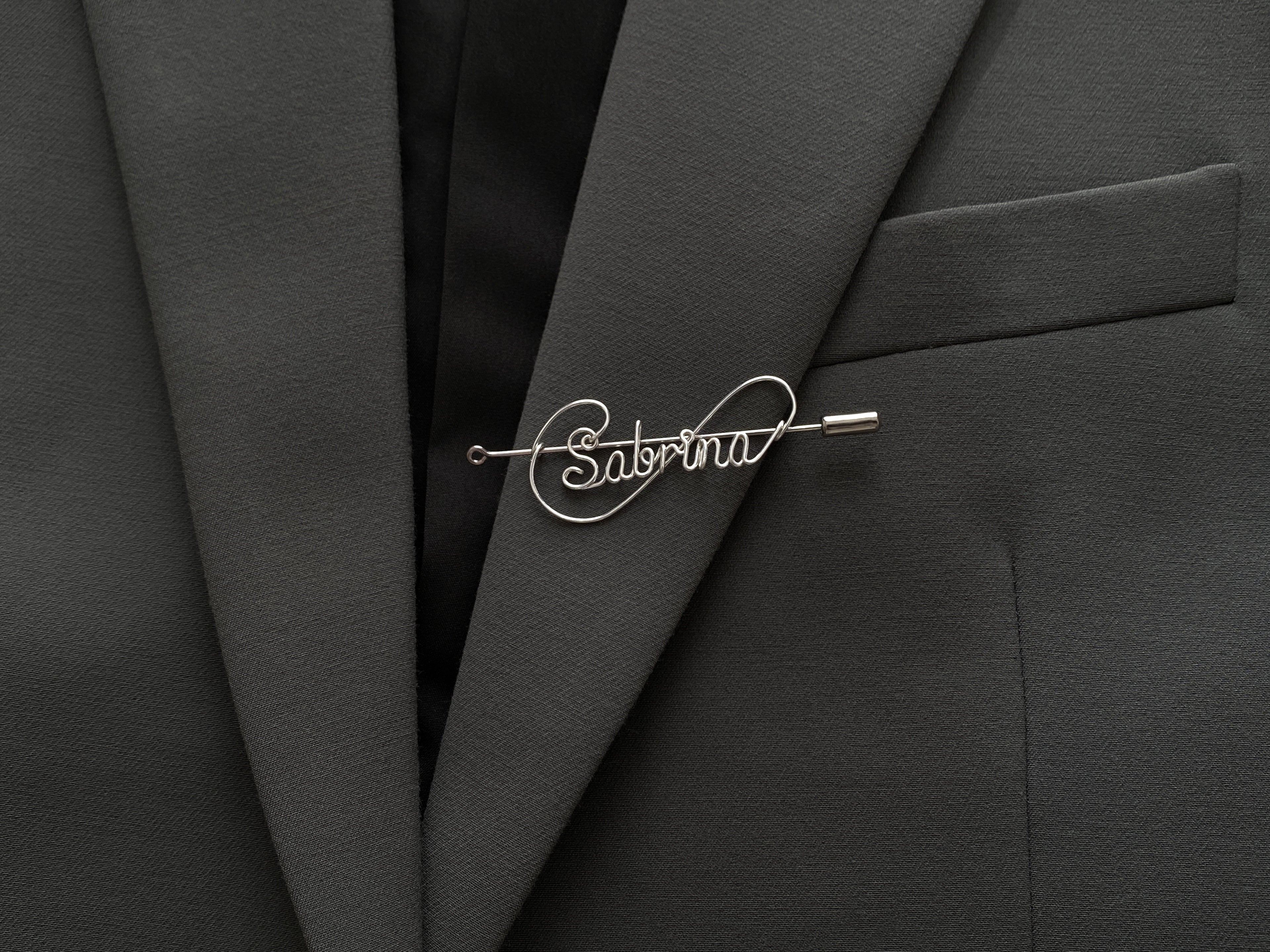 Modern infinite-line design personalized name pin, crafted in silver-plated finish on a dark green jacket.