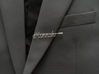 Minimalist personalized name pin, handmade in silver-plated finish on a dark green jacket.
