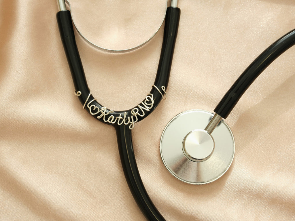 Personalized silver stethoscope name tag featuring "Katly RN" and heart symbols, a professional accessory for nurses.