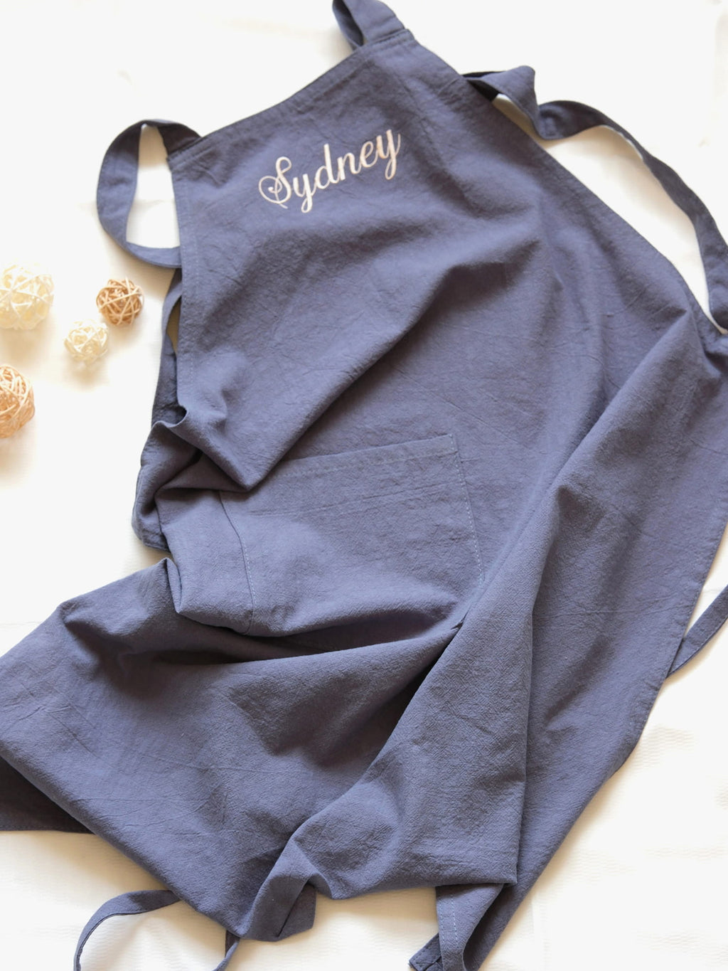 Slate Blue linen apron personalized with "Sydney" embroidery and a spacious central pocket.