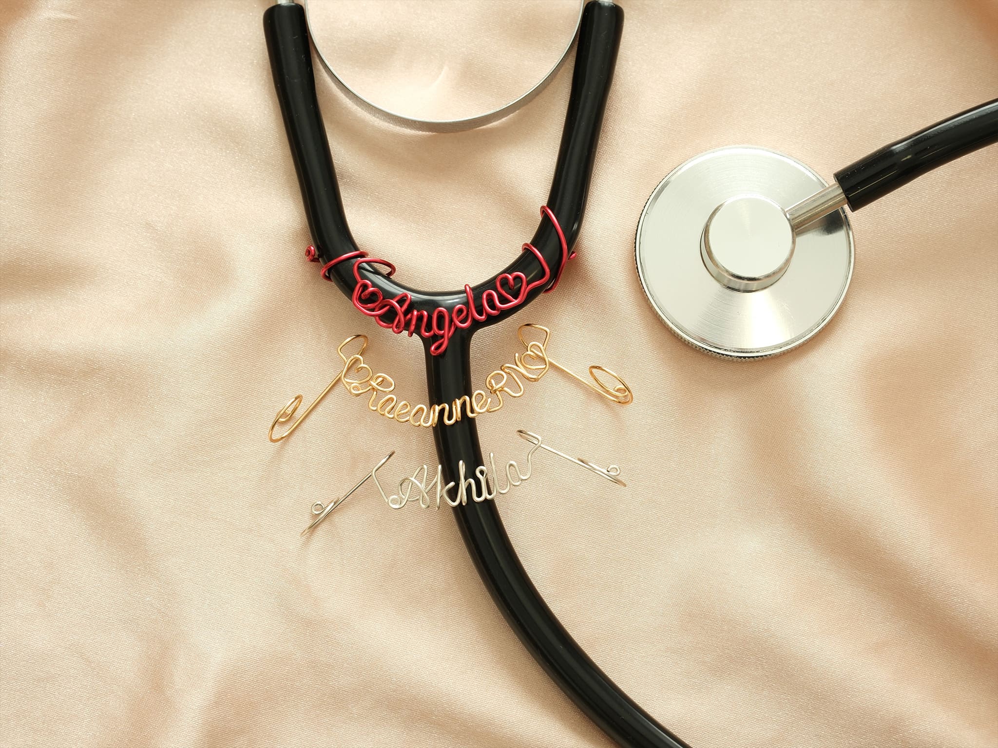 Three personalized stethoscope name tags in red, gold, and silver metal—an ideal gift for doctors and nurses.