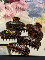 Personalized tortoise shell hair claw clip with a name in white rhinestones, elegant vintage style.
