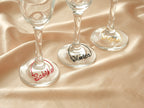 Personalized wine glass charms in red, black, and gold metal, perfect for distinguishing guests' drinks.