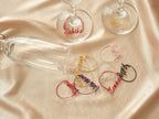 Creative display of personalized wine glass charms in various colors, an original gift idea for wedding favors or parties.