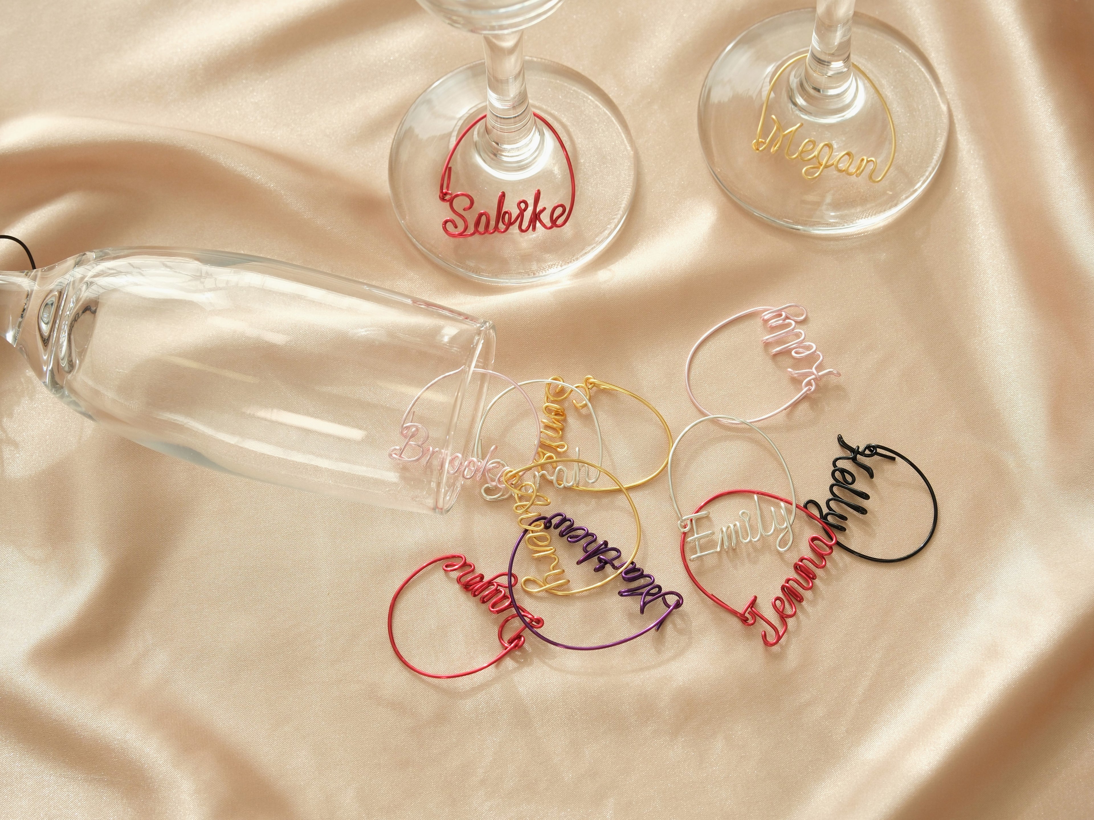 Creative display of personalized wine glass charms in various colors, an original gift idea for wedding favors or parties.